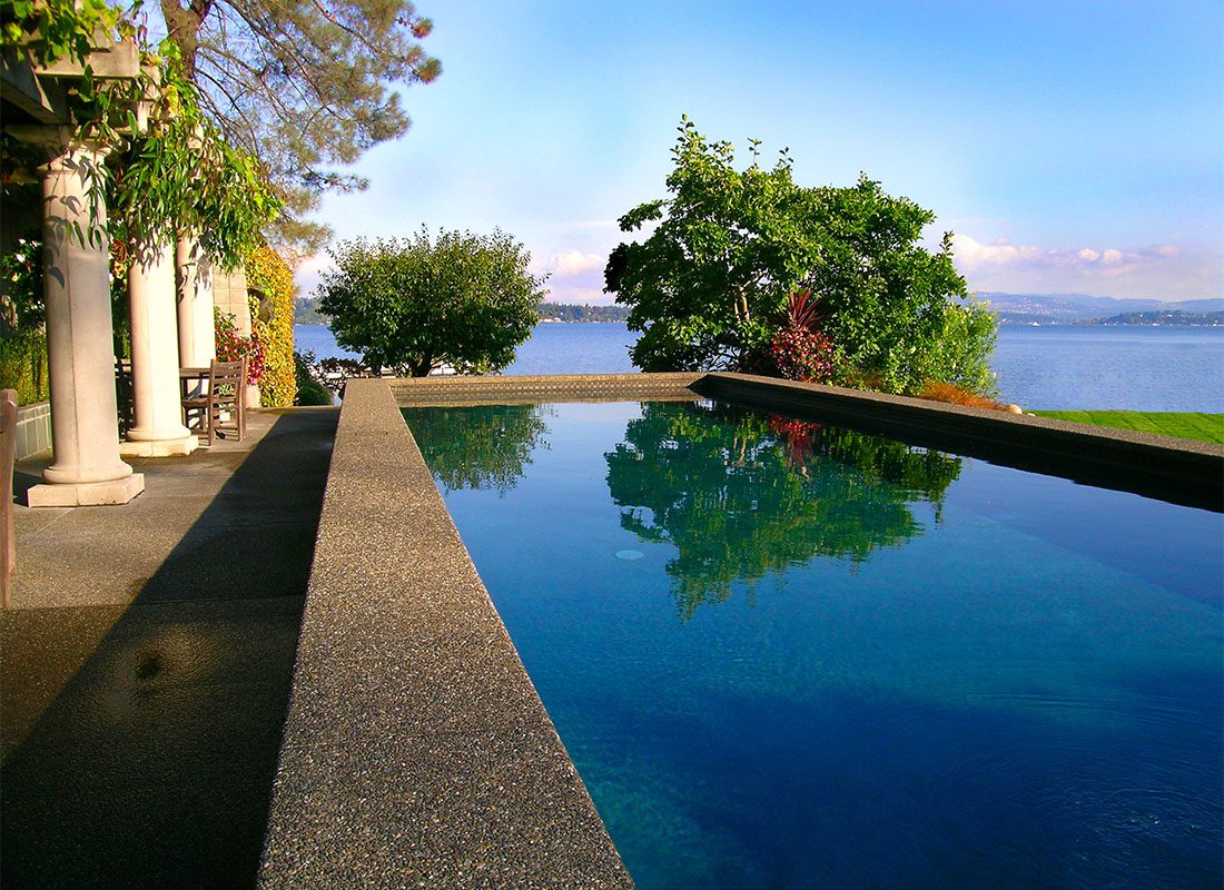 We Are Independent - Scenic View of a Luxury Modern Pool Overlooking the Lake Surrounded by Bright Green Foliage